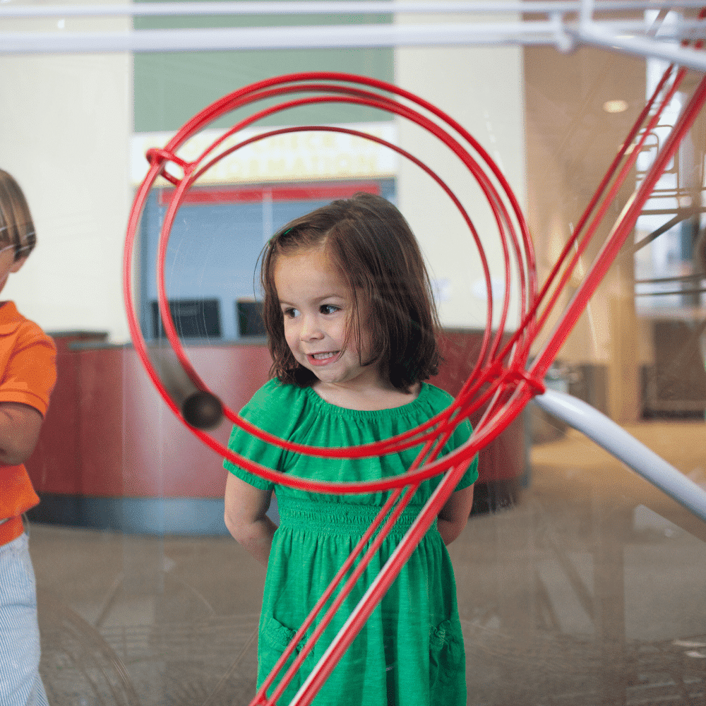 Child explores kinetic ball machine at children's science center interactive STEM exhibit