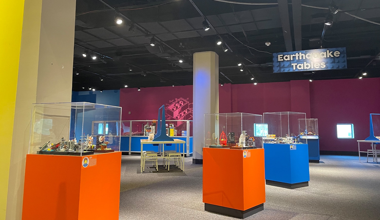 Earthquake Tables exhibit at children's science center with colorful interactive displays and models in glass cases.