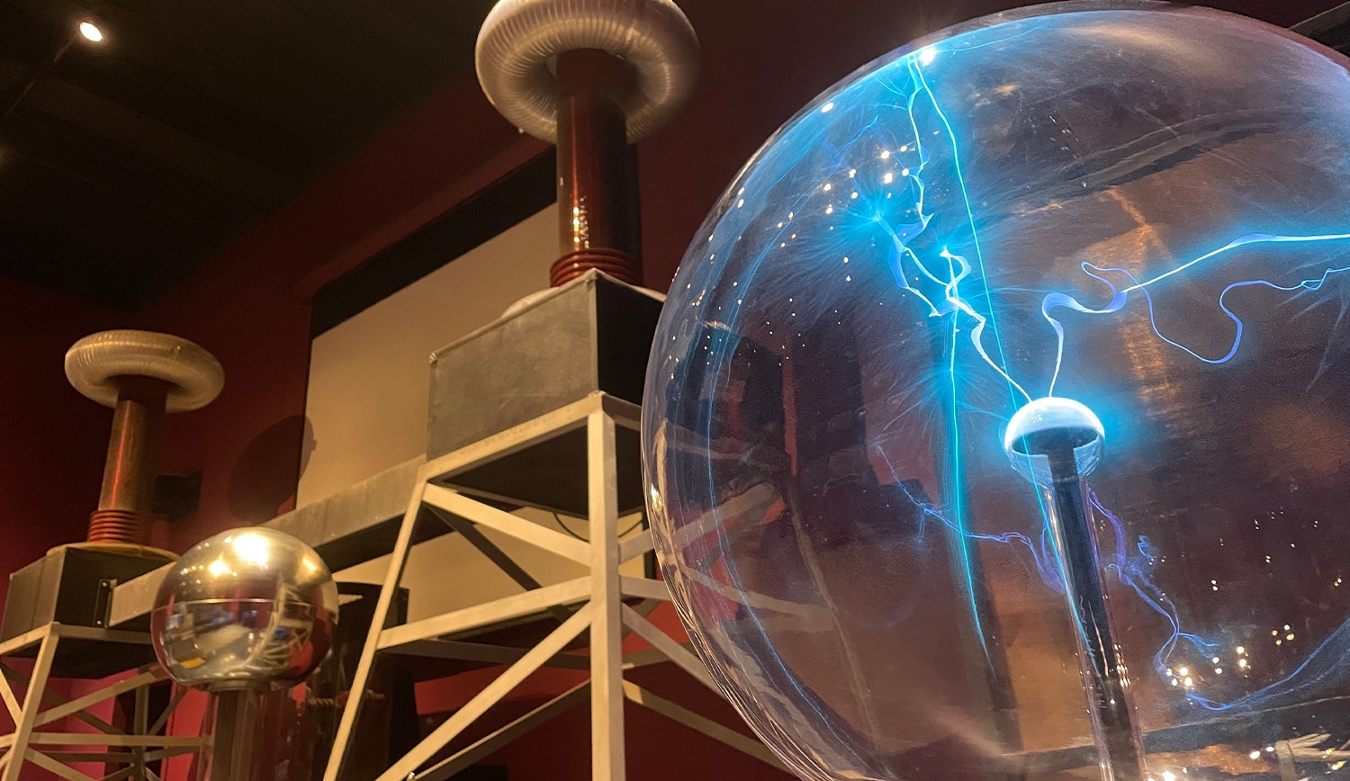 Plasma globe and Tesla coils at children's science center electricity exhibit, glowing blue arcs for hands-on STEM fun