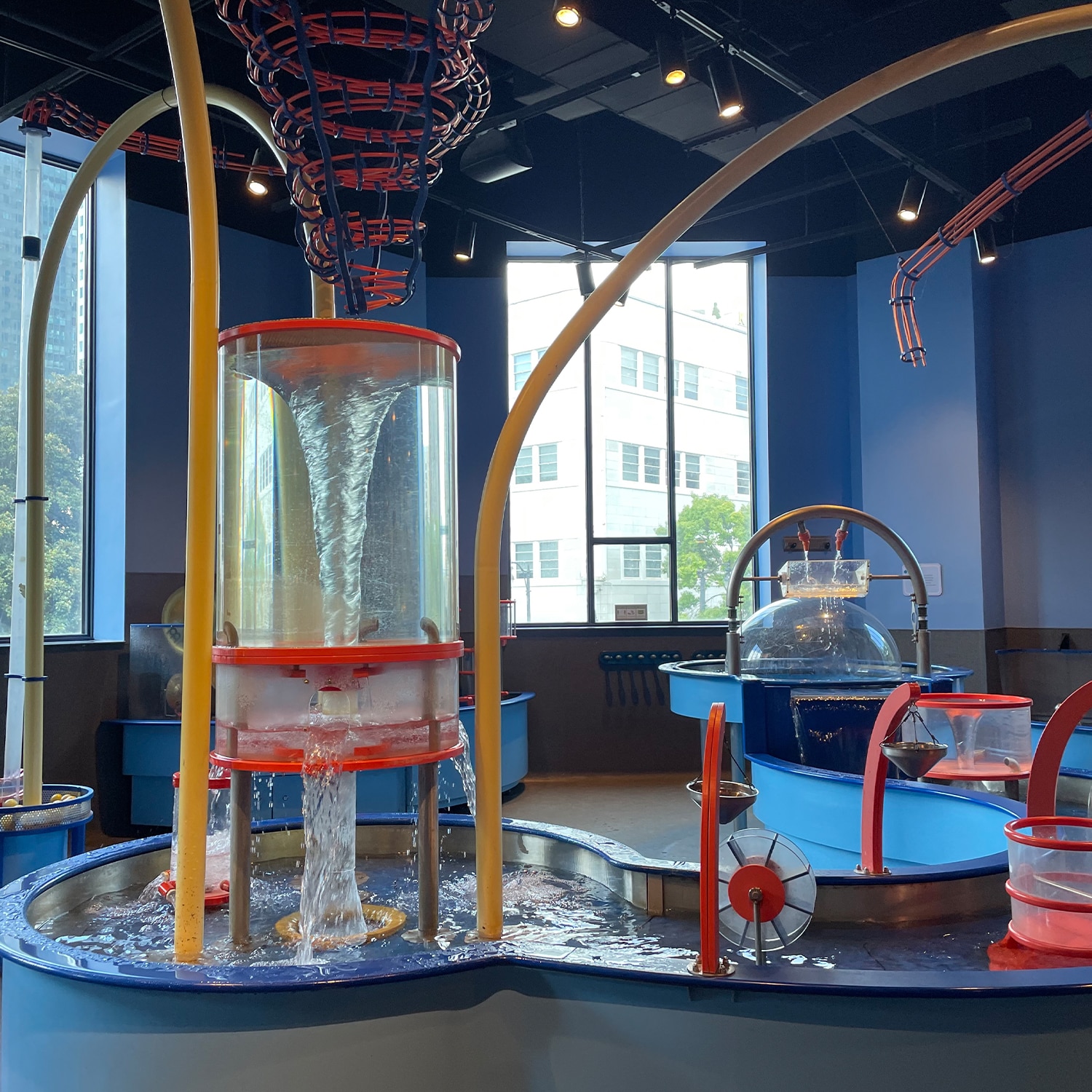 Interactive water exhibit at children's science center with vortex tank, pumps, and water wheels for hands-on STEM play.