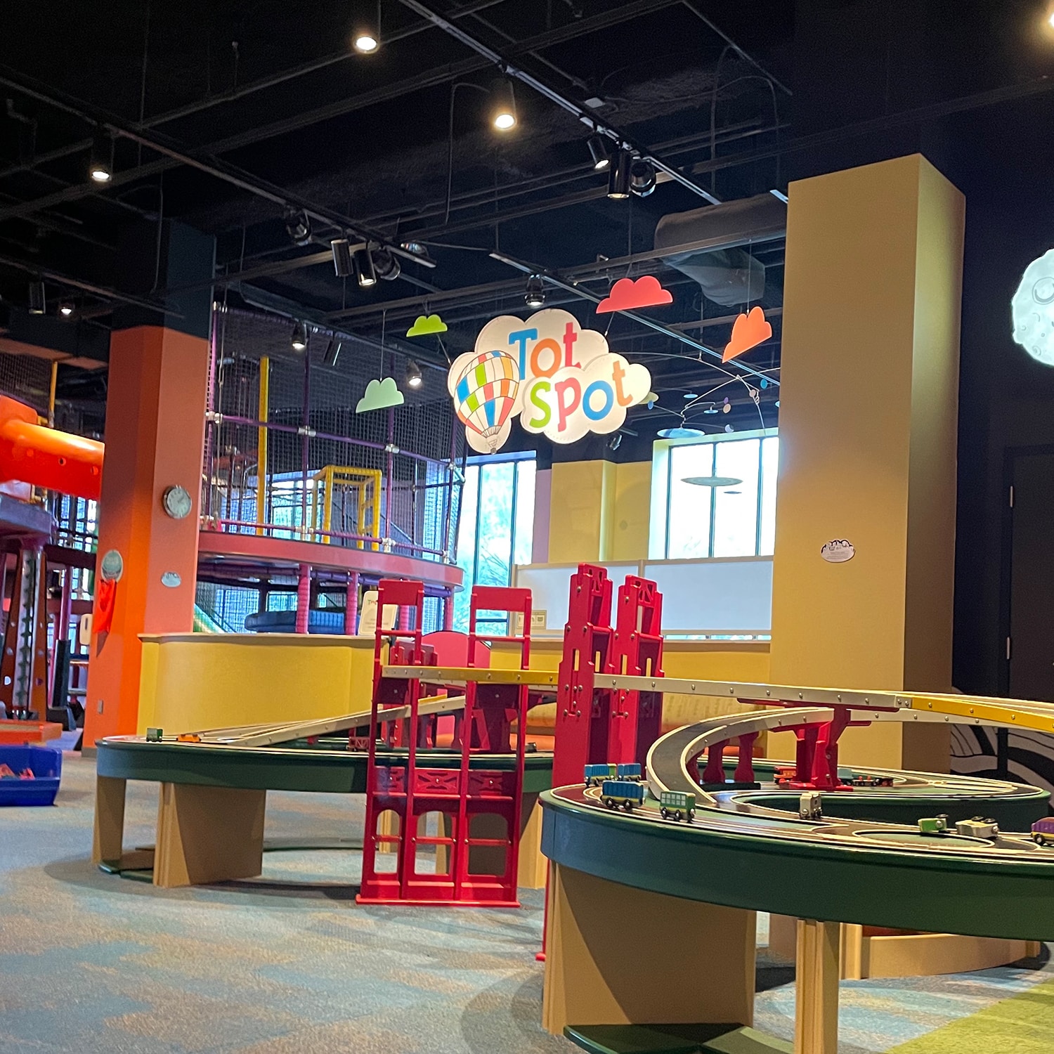 Tot Spot play area at children's science center with toy train tables and indoor climbing structure