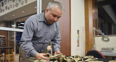 A man examines dinosaur fossils during a hands-on paleontology demo at the children's science center.