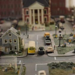 Miniature city street with school bus, cars, and town hall at a children's science center STEM model exhibit.