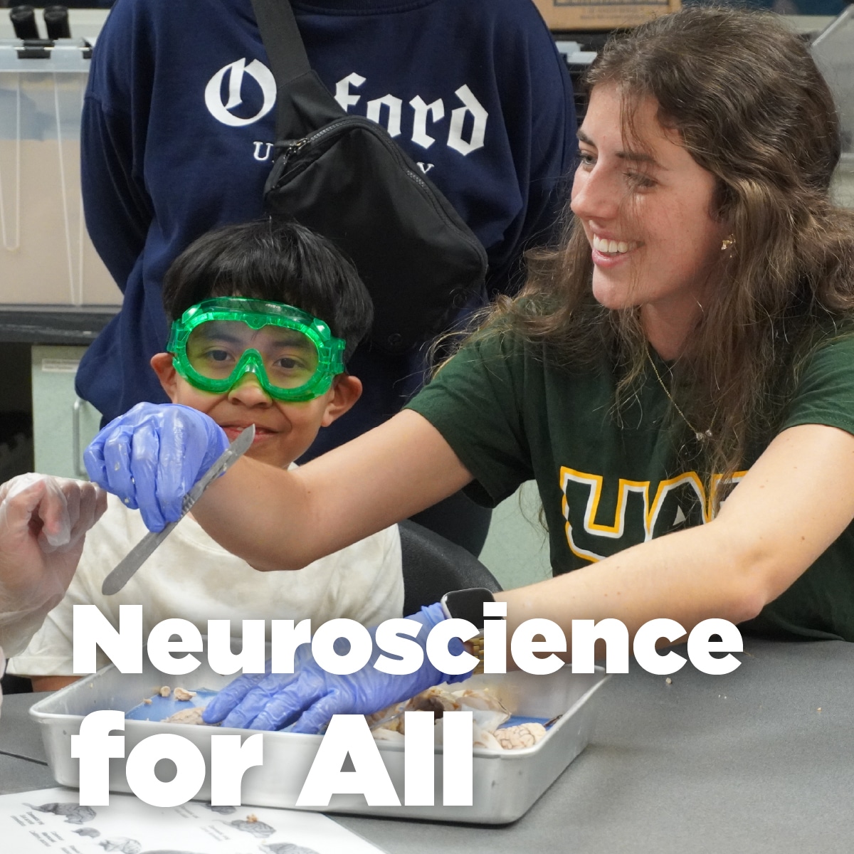 Child in goggles and an educator dissect a brain at children's science center hands-on neuroscience workshop.